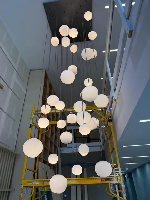 Cascading globe pendants in a three-story atrium, mid-install
